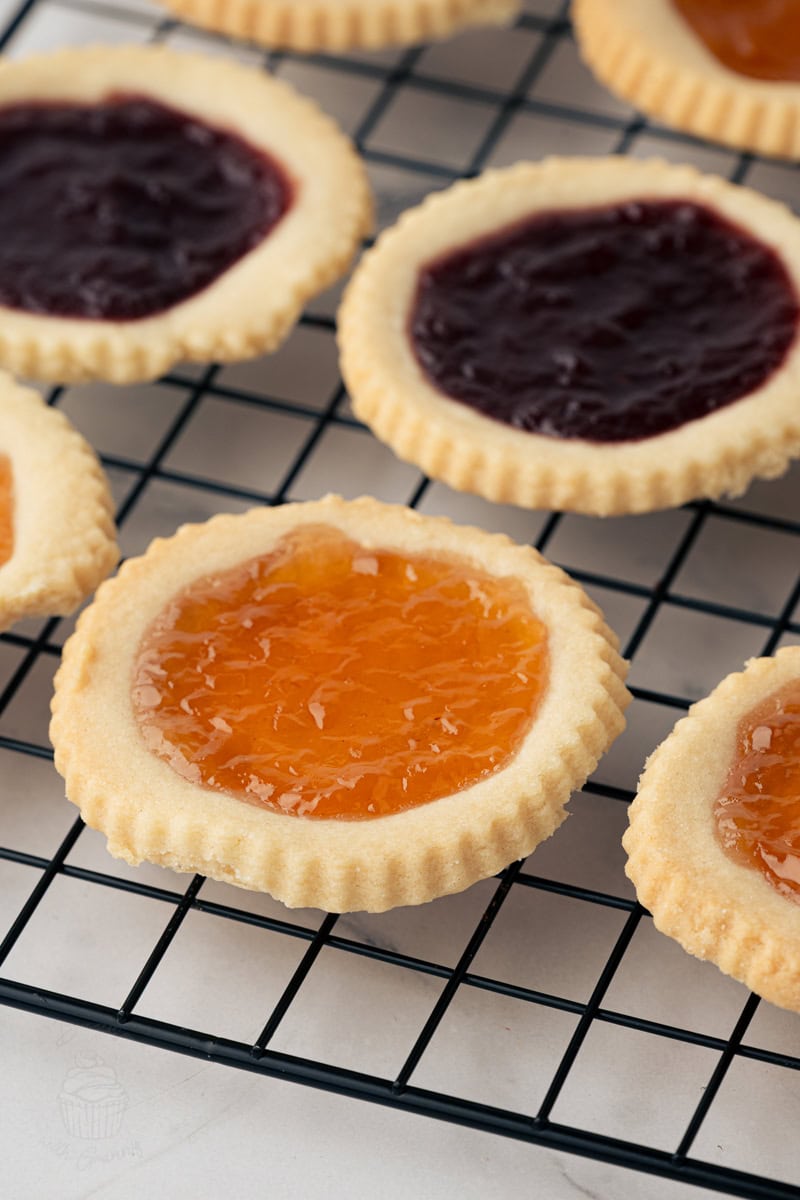 Close-up of apricot jam tart on a cooling rack with other jam tarts in the background