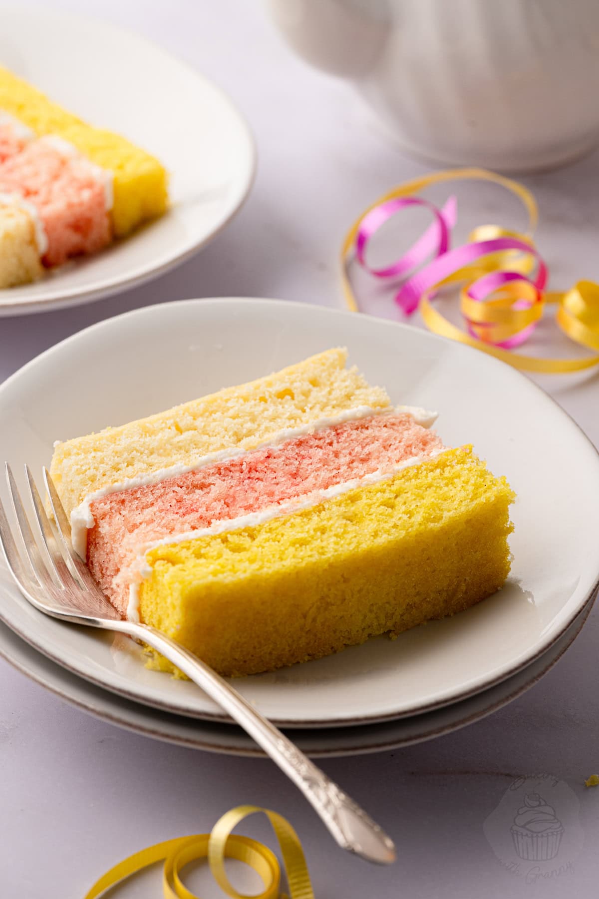Slice of Angel Cake with three colourful sponge layers and buttercream filling.