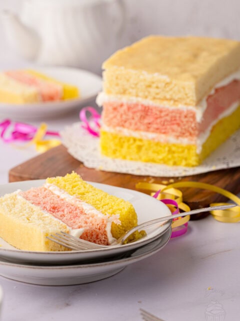 Angel Cake on a wooden board with a slice served in the background.