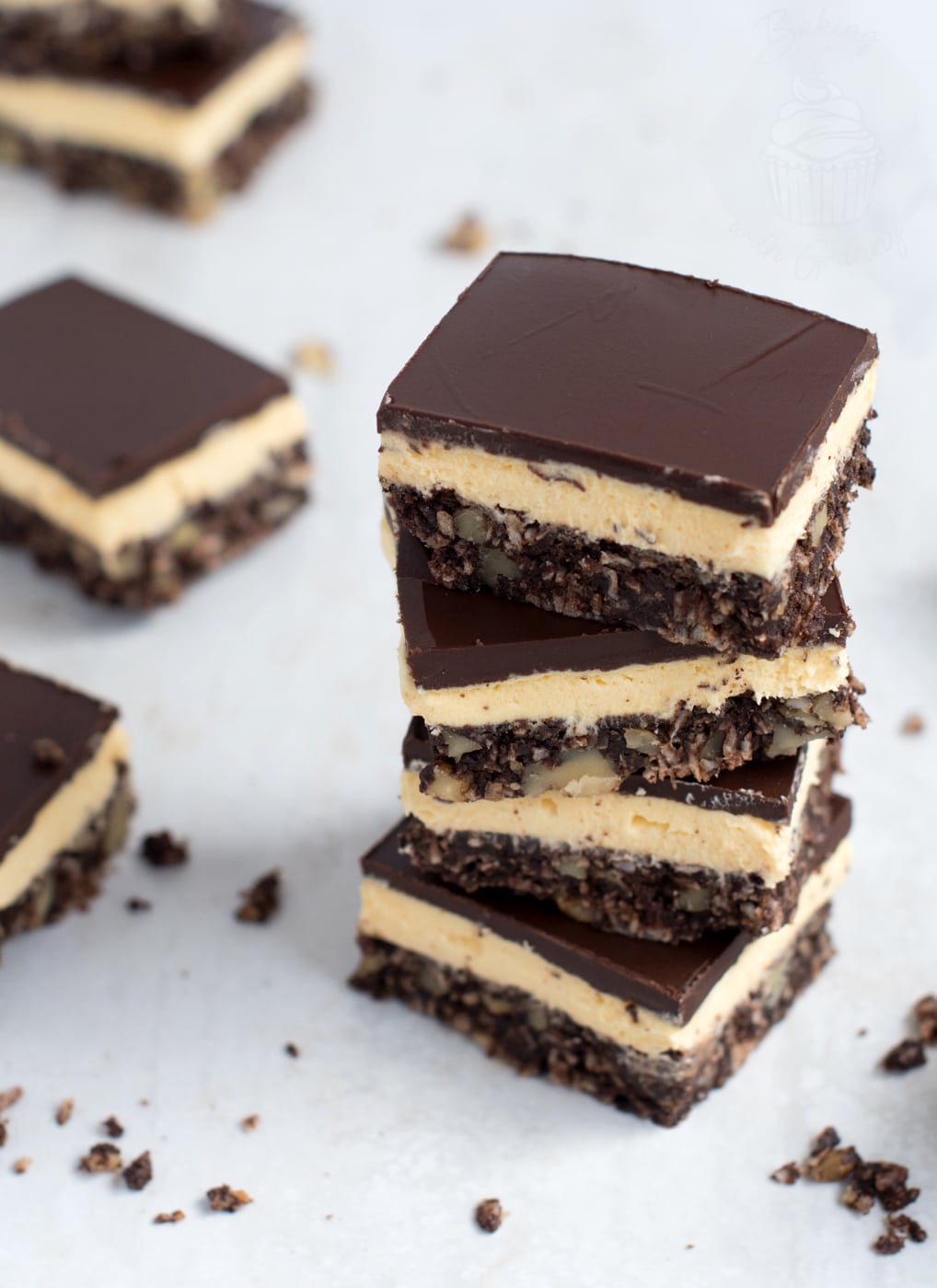 A vertical stack of sliced Nanaimo bars displaying the smooth chocolate top layer, pale yellow custard middle, and textured base.