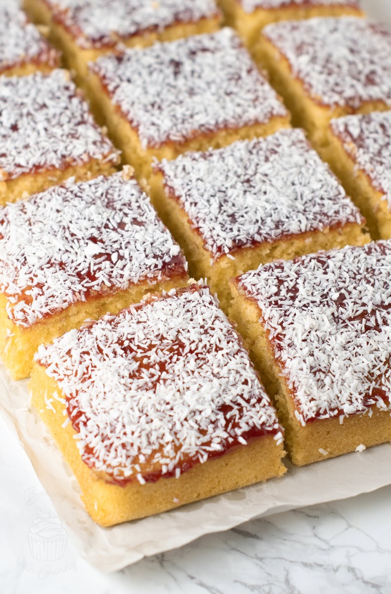 Squares of jam and coconut school cake topped with raspberry jam and desiccated coconut.