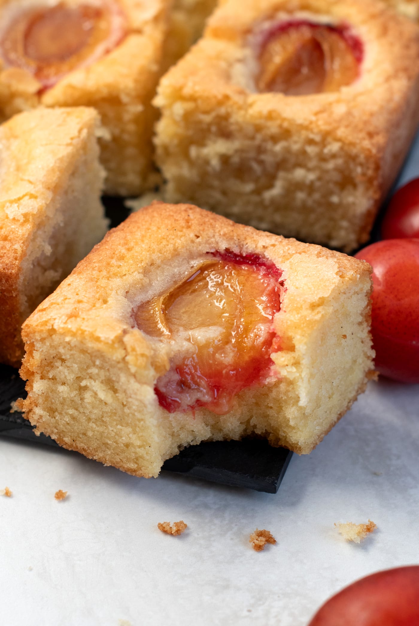 Slices of plum cake showing yellow sponge and baked plum halves.
