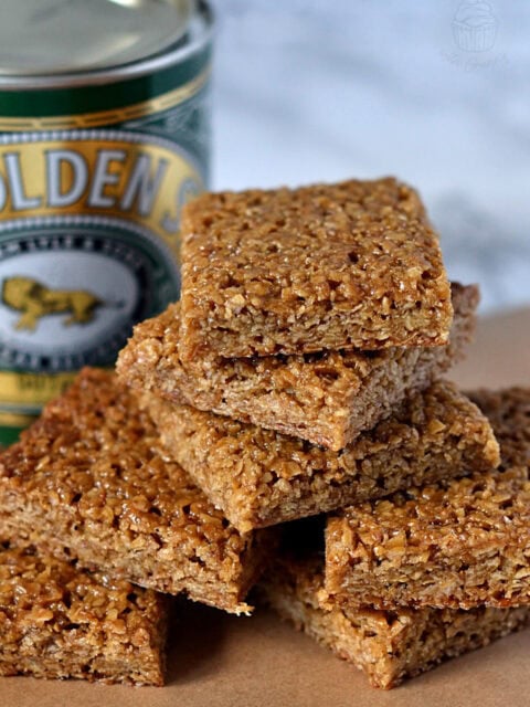 Stack of flapjack squares beside a tin of Lyle’s Golden Syrup.