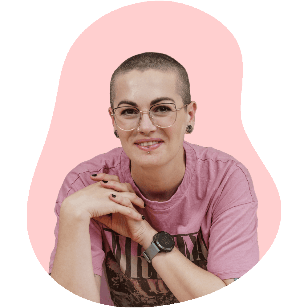 Headshot photo of Amy Beth Reid, the creator of Baking with Granny. Amy has a shaved head, wears glasses and has a pink Nirvana t-shirt on.