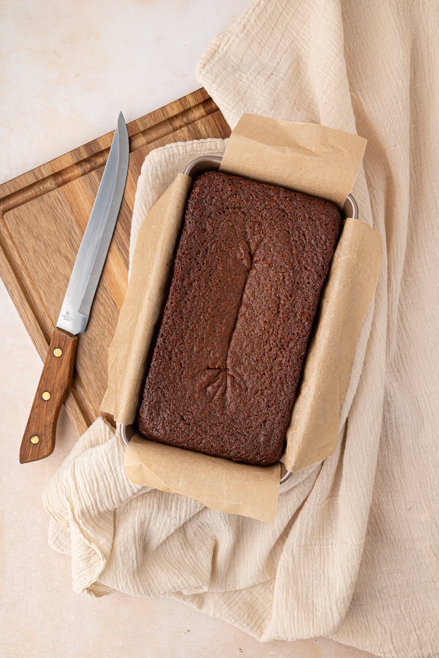 Freshly baked gingerbread loaf cooling in a lined loaf tin.