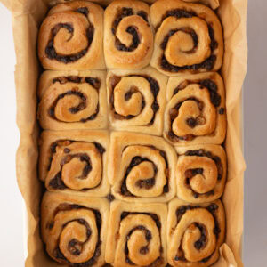 Overhead view of freshly baked Chelsea Buns in a lined baking dish before serving.