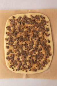 Unrolled Chelsea Bun dough topped with spiced butter, currants and sultanas before shaping.