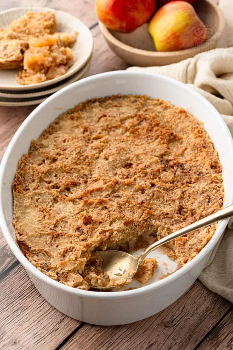 An easy apple crisp recipe baked to a perfect crisp crust, showing a gold spoon scooping out a serving.