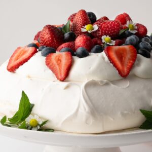Pavlova topped with whipped cream, strawberries, raspberries and blueberries.