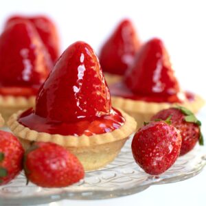 Scottish strawberry tarts with cream, fresh strawberries and sticky strawberry sauce.