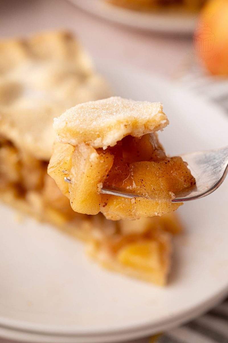 Forkful of apple pie showing chunky apple filling and golden shortcrust pastry.