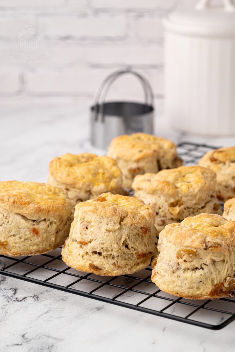 Fluffy homemade Fruit Scones cooling on a wire rack, with a white sugar jar and cutter in the background.